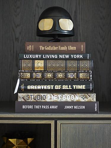 Stack of books with bronze helmet by Studio Molen (Frederik Molenschot) on top in custom made bookcase